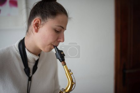 Foto de Hermosa joven tocando el saxofón en la habitación - Imagen libre de derechos