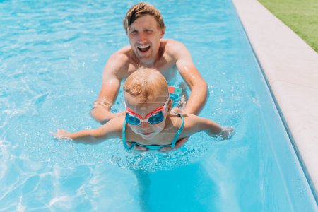 Foto de Padre e hijas jugando en la piscina al aire libre - Imagen libre de derechos