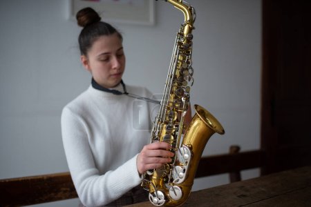 Foto de Mujer joven montando un saxofón para empezar a tocar música. - Imagen libre de derechos