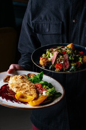 Foto de Un hombre sostiene un plato en el que un schnitzel de pollo. menú del restaurante - Imagen libre de derechos