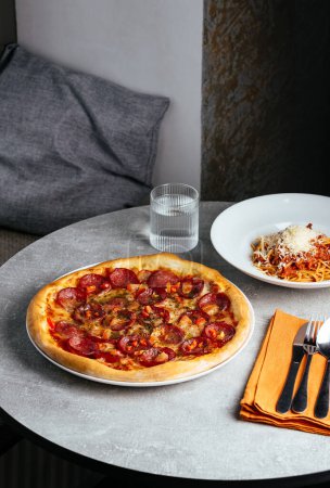 Téléchargez les photos : Pizza pepperoni sur une assiette dans un restaurant sur la table - en image libre de droit