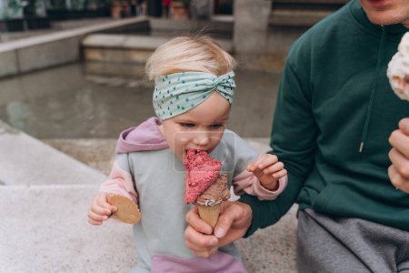 Foto de Papá alimenta a su hija con helado de bayas en un cono de gofre, primer plano - Imagen libre de derechos