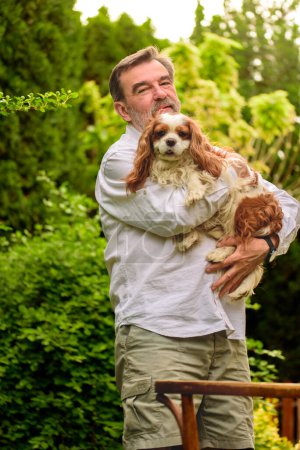 Téléchargez les photos : Portrait d'un homme âgé avec son chien dans le jardin. - en image libre de droit