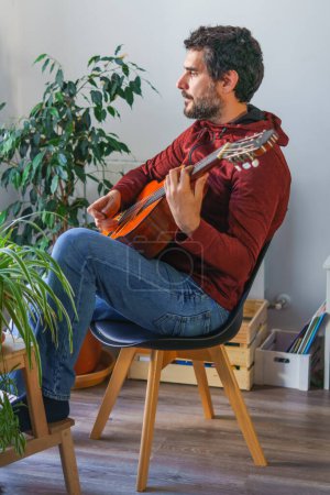 Foto de Hombre tocando la guitarra española sentado en una silla - Imagen libre de derechos