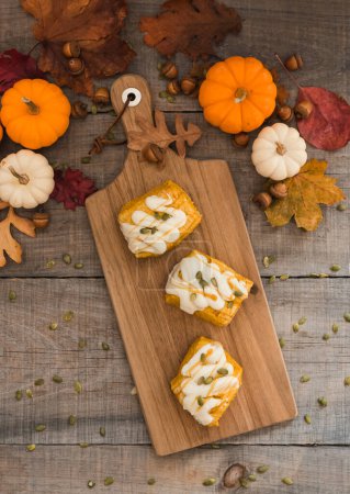 Photo for Overhead view of pumpkin scones on wooden board on a rustic table. - Royalty Free Image
