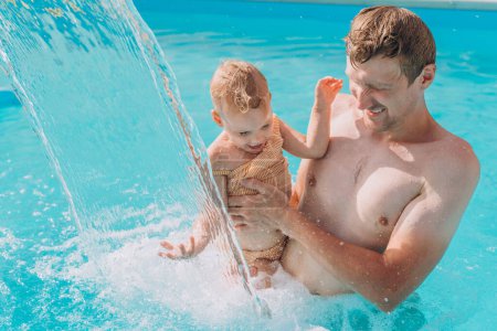 Téléchargez les photos : Un homme avec une fillette nage dans une piscine extérieure avec hydromassage - en image libre de droit