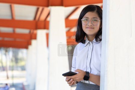 Téléchargez les photos : Écolière en utilisant smartphone et smartwatch à l'école - en image libre de droit