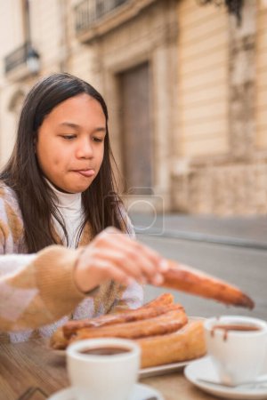 Photo for Teenage girl eating delicious churros with chocolate. - Royalty Free Image