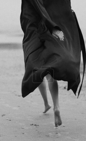 Photo for Girl in bathrobe walking on the beach - Royalty Free Image