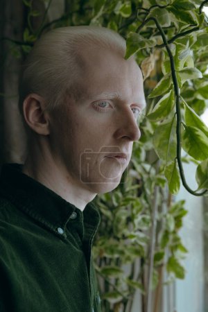 Foto de Un tipo albino con plantas verdes sobre un fondo oscuro - Imagen libre de derechos