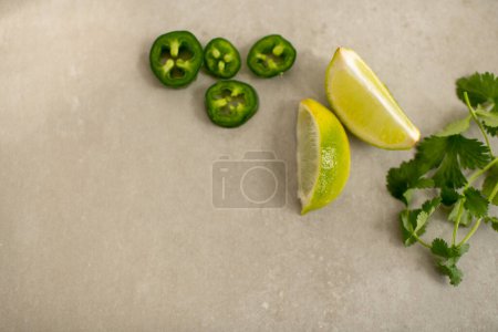 Photo for Jalapeos and Lime Slices and Cilantro Branches on Kitchen Table Top - Royalty Free Image
