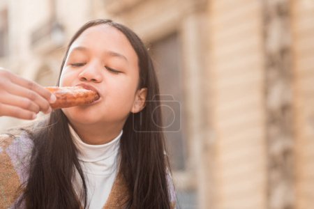 Photo for Close up young brunette teenager enjoying eating churros - Royalty Free Image