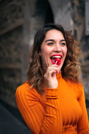 Photo for Attractive young woman eating lollipops in the street - Royalty Free Image