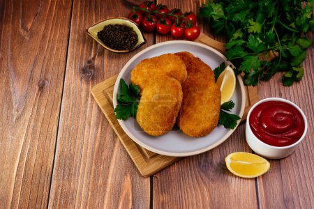 Photo for Chicken cutlets on a plate. vegetables and herbs. wooden table - Royalty Free Image