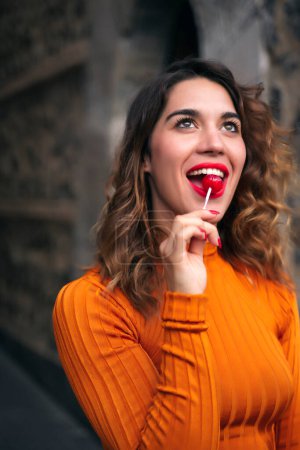 Photo for Attractive young woman eating lollipops in the street - Royalty Free Image