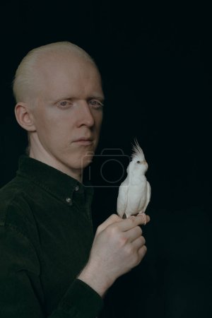 Foto de Un tipo albino con un loro blanco sobre un fondo oscuro - Imagen libre de derechos