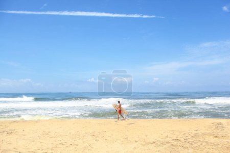 Foto de Un hombre caminando por la playa con una tabla de surf - Imagen libre de derechos