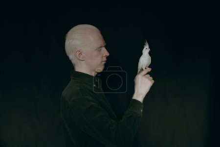 Foto de Un tipo albino con un loro blanco sobre un fondo oscuro - Imagen libre de derechos