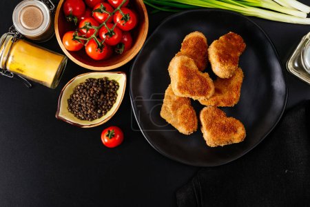 Téléchargez les photos : Escalopes de poulet sur une assiette noire. légumes et herbes. fond noir - en image libre de droit