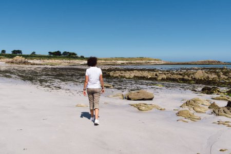 Téléchargez les photos : Portrait complet d'une femme d'âge moyen marchant sur la plage - en image libre de droit