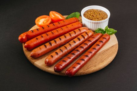 Photo for Grilled sausages on a wooden board. Vegetables and sauce. - Royalty Free Image