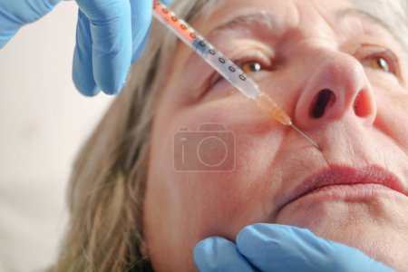 Foto de Mujer mayor recibe inyección en sus labios. . - Imagen libre de derechos