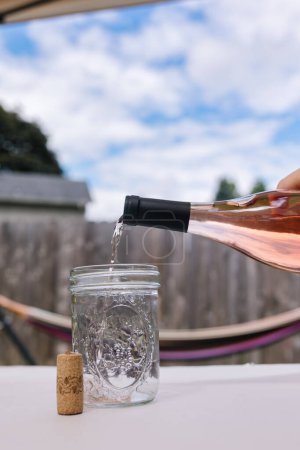 Photo for Beautiful blue sky with puffy clouds and rose wine being poured - Royalty Free Image