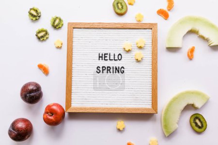 Téléchargez les photos : Hello Spring planche aux lettres de devis avec des tranches lumineuses de fruits frais - en image libre de droit