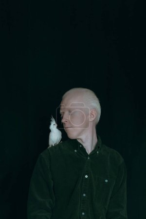 Téléchargez les photos : Un albinos avec un perroquet blanc sur fond sombre - en image libre de droit