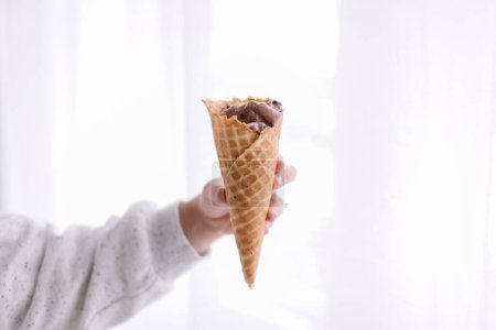 Photo for Hand holding waffle cone with chocolate ice cream, inside - Royalty Free Image