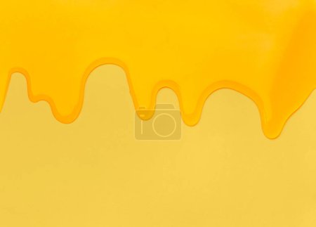 Foto de Flowing drops of honey on a yellow background with space for text. Abstraction from honey drips. Fluid yellow sludge. - Imagen libre de derechos
