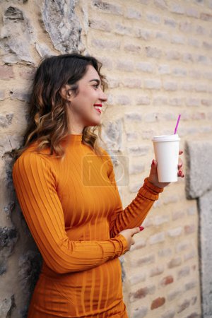 Téléchargez les photos : Attrayant jeune femme boire du café dans la rue - en image libre de droit