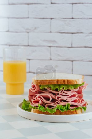 Photo for Sandwich with ham, cheese and herbs on a plate. orange juice in a glass - Royalty Free Image