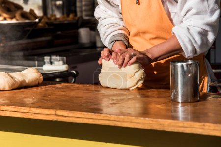 Téléchargez les photos : Détail du travailleur pétrissant la pâte fraîche pour préparer des beignets espagnols au stand de la rue. - en image libre de droit