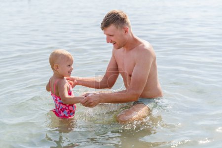 Photo for Happy man and baby girl toddler in the sea - Royalty Free Image