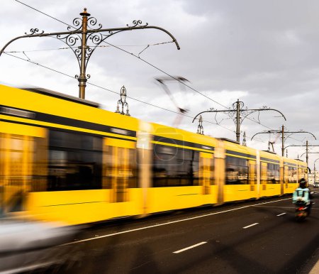 Téléchargez les photos : Photo de stock de tram en mouvement passant par une personne à moto - en image libre de droit