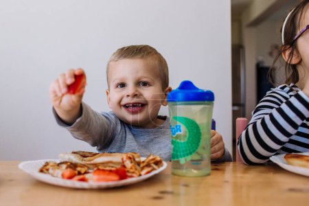 Foto de Niños pequeños comiendo una comida en una mesa - Imagen libre de derechos
