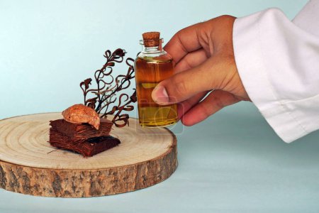 Téléchargez les photos : Concept de médecine naturelle : Médecin prenant un bocal avec de l'huile essentielle sur un fond bleu. Médecine alternative et plantes médicinales
. - en image libre de droit