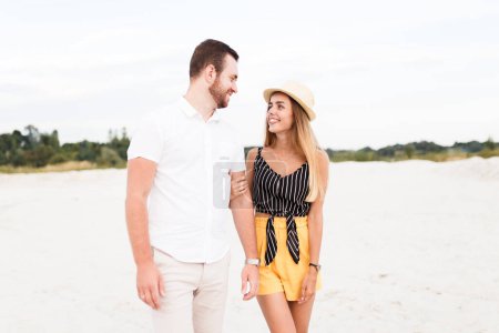 Téléchargez les photos : Homme et femme marchent sur la plage de sable chaud en été en vacances - en image libre de droit