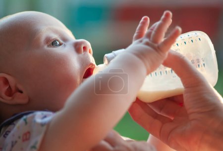 Photo for A small child drinks milk from a bottle. - Royalty Free Image