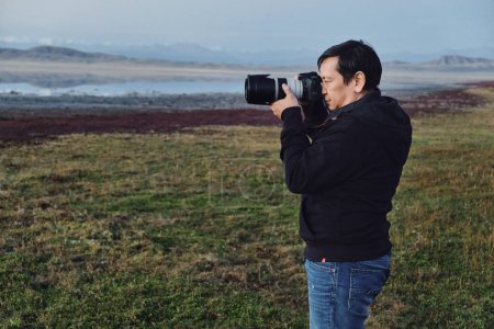 Foto de Hombre fotógrafo de la naturaleza con una cámara dispara un paisaje - Imagen libre de derechos