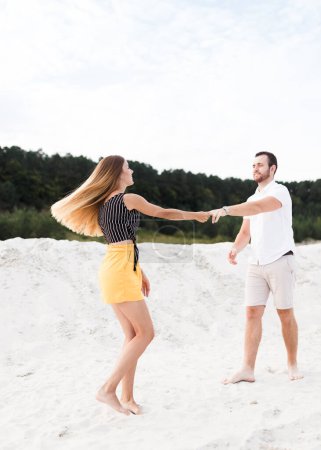Homme et femme dansant sur une plage de sable chaud en été