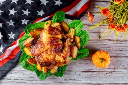 Photo for Thanksgiving celebration dinner with golden roast chicken and USA flag - Royalty Free Image