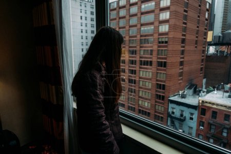 Photo for Woman looking at city out of window - Royalty Free Image