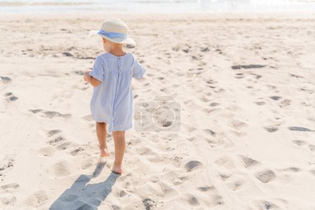 Foto de Niña en un sombrero de paja en la playa junto al mar, vista trasera - Imagen libre de derechos