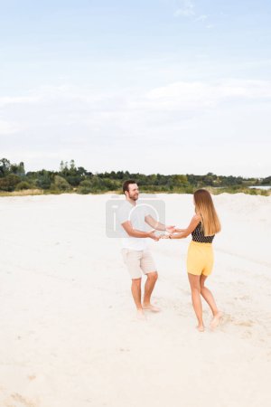 Hombre y mujer bailando en una playa de arena caliente en verano