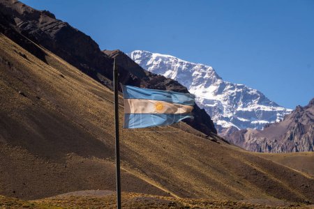 Drapeau argentin flottant dans le vent, derrière la colline de l'Aconcagua à Mendoza Argentine