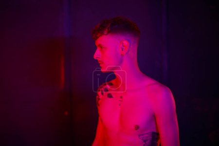 Photo for Portrait of nude young man in profile under purple red light - Royalty Free Image
