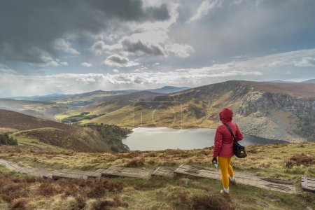 Foto de Mujer montañista admirando paisaje montañoso con un lago - Imagen libre de derechos