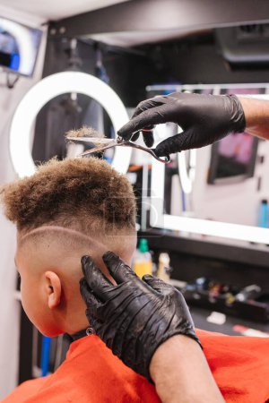 Téléchargez les photos : Latino soirée coiffeur cheveux bouclés sur garçon biracial avec des ciseaux - en image libre de droit